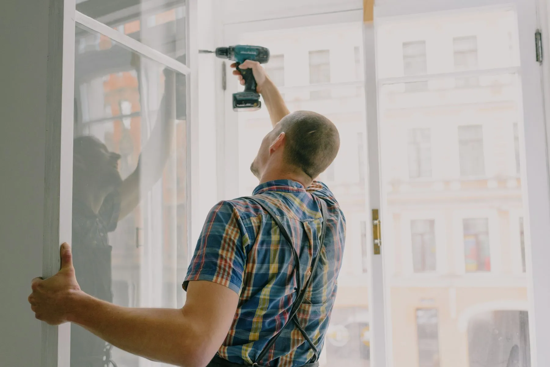Instalador colocando una ventana con taladro