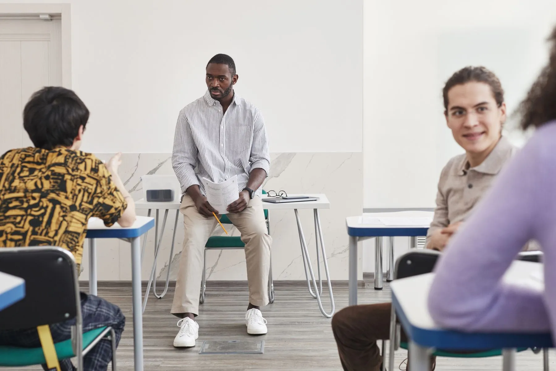 Profesor conversando con un grupo de alumnos adultos en un aula moderna