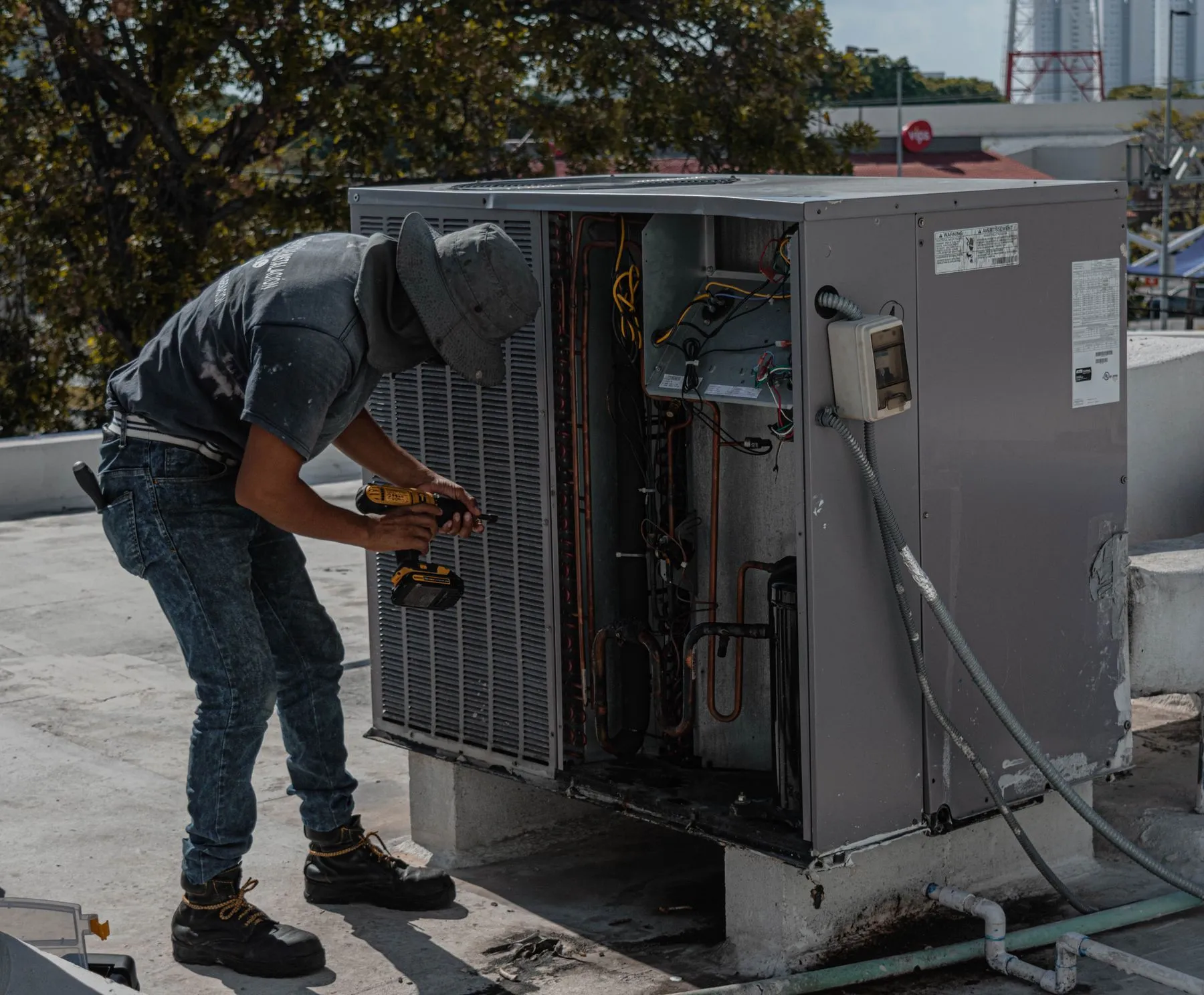 Técnico reparando una unidad exterior de aire acondicionado en una azotea