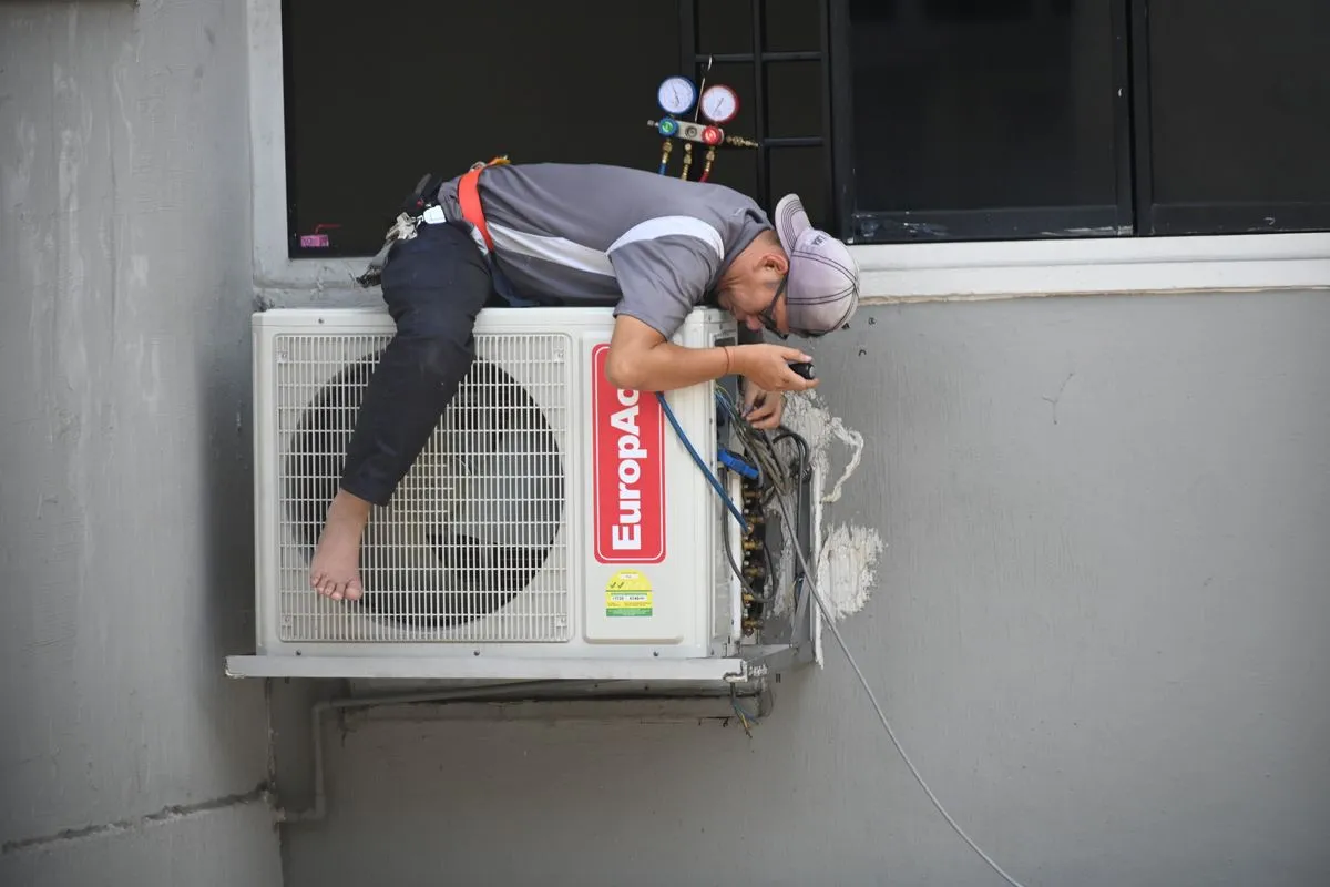 Técnico instalando la unidad exterior de un split en la pared de un edificio