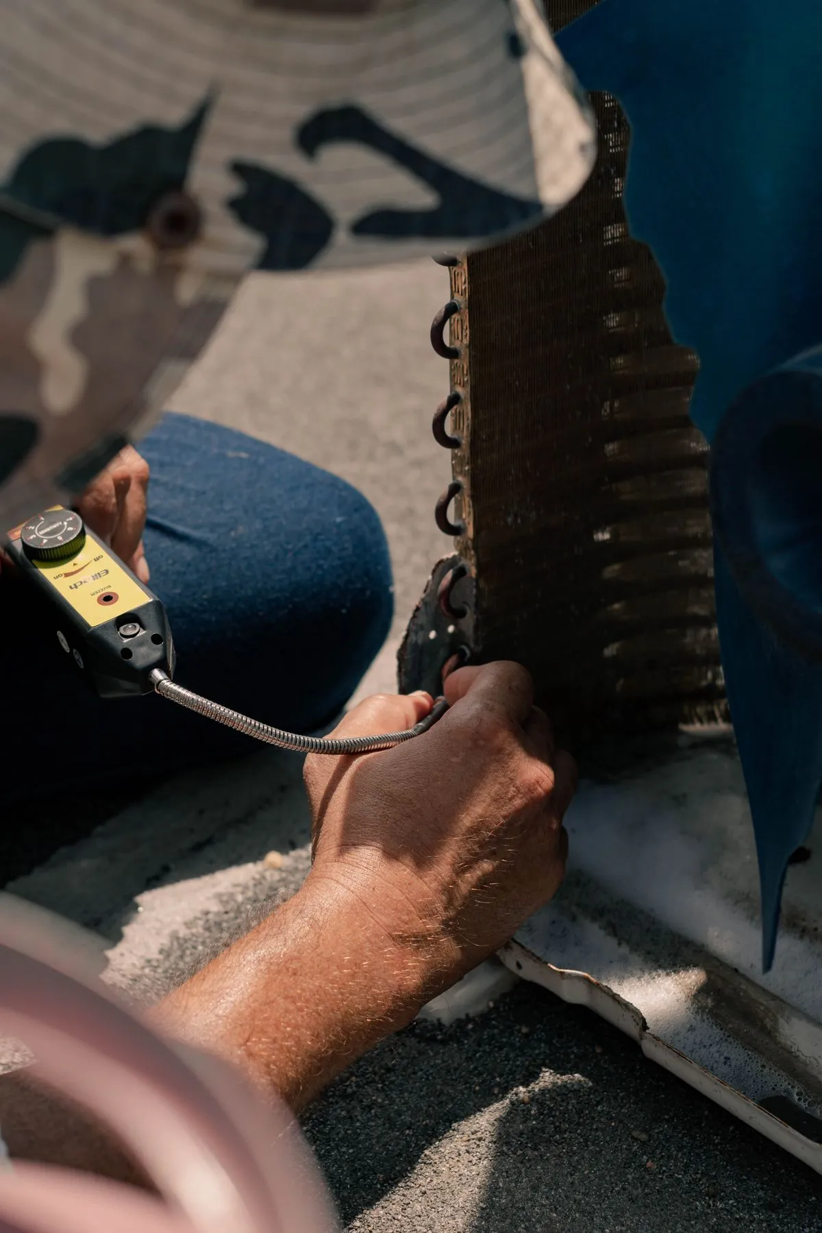Manos de técnico trabajando dentro de una unidad exterior con herramientas