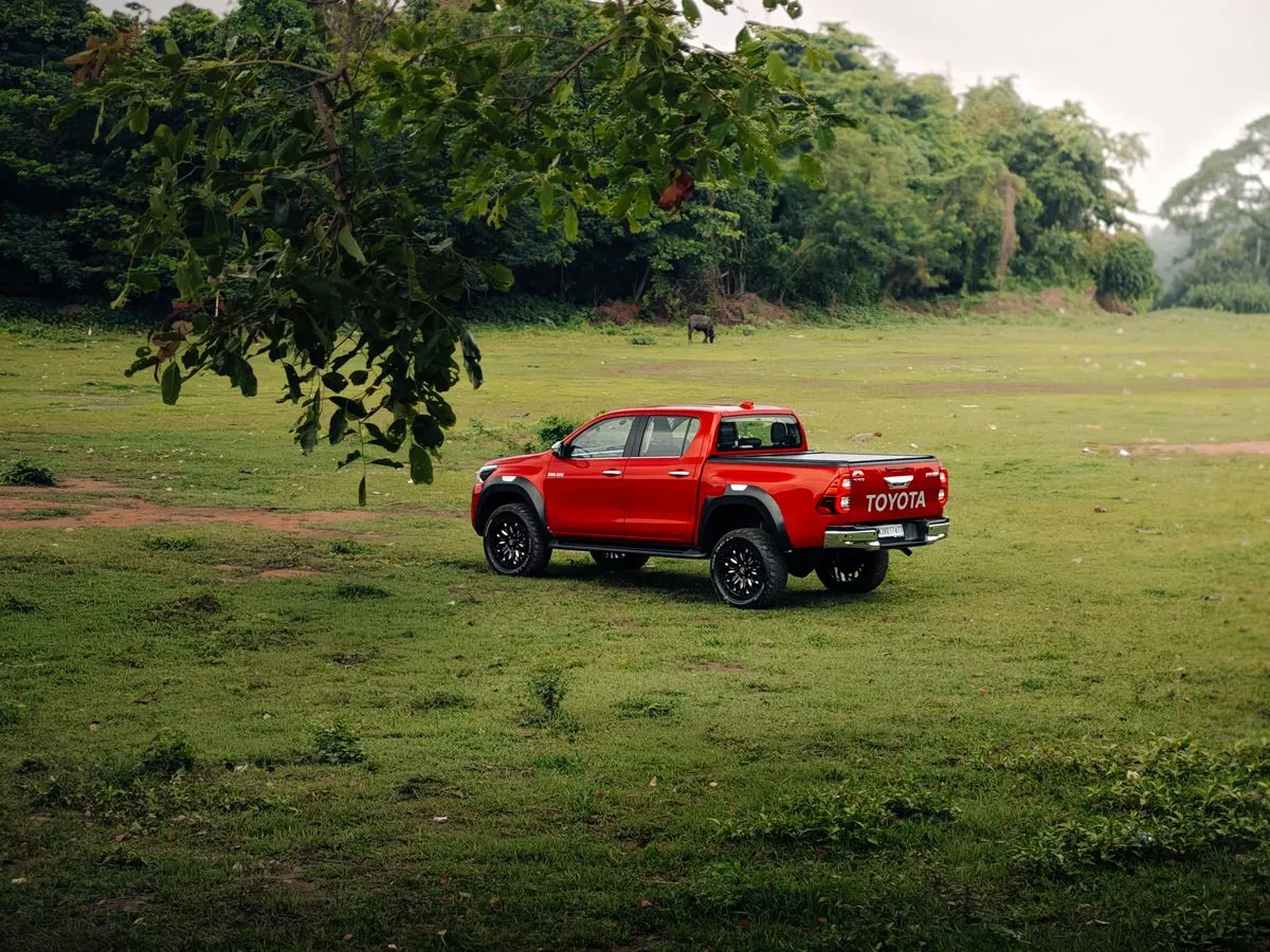 Camioneta Toyota Hilux doble cabina roja estacionada en el pasto