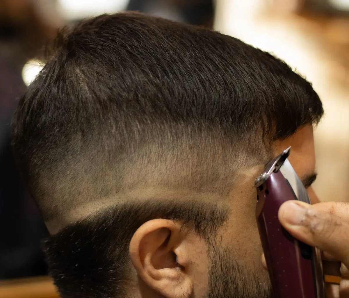 Barbero marcando un degradé con máquina en la nuca de un cliente