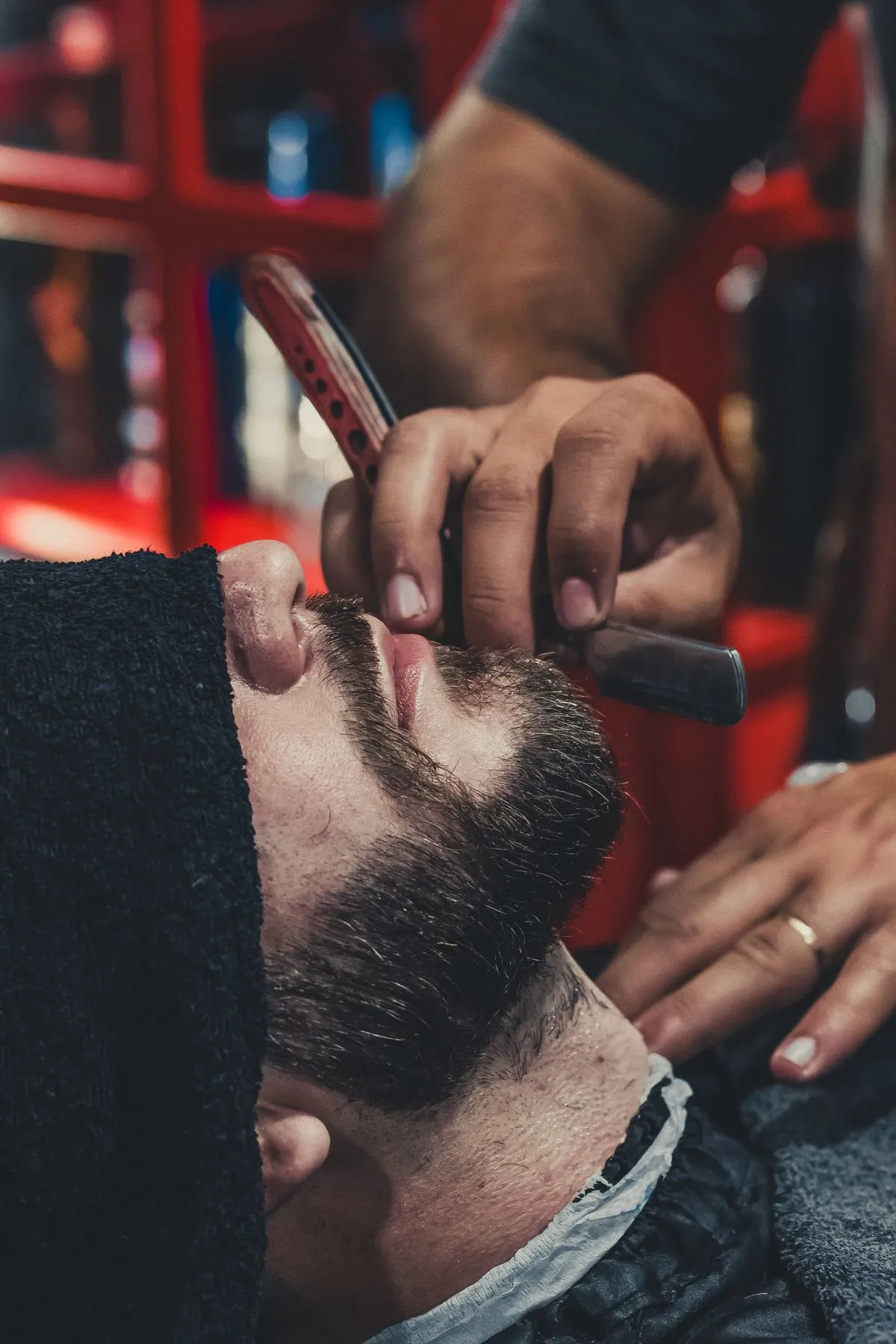 Barbero afeitando con navaja el cuello de un cliente con barba