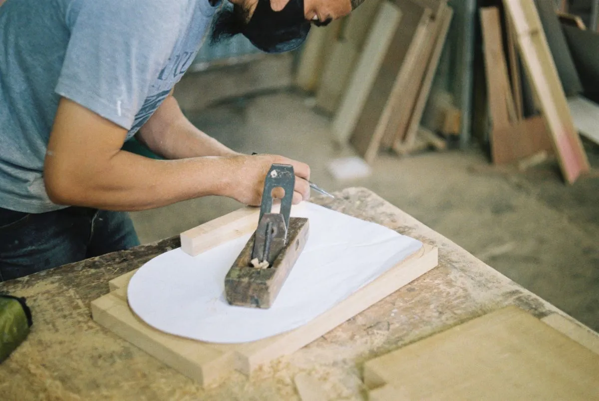 Carpintero cepillando una pieza de madera en el taller