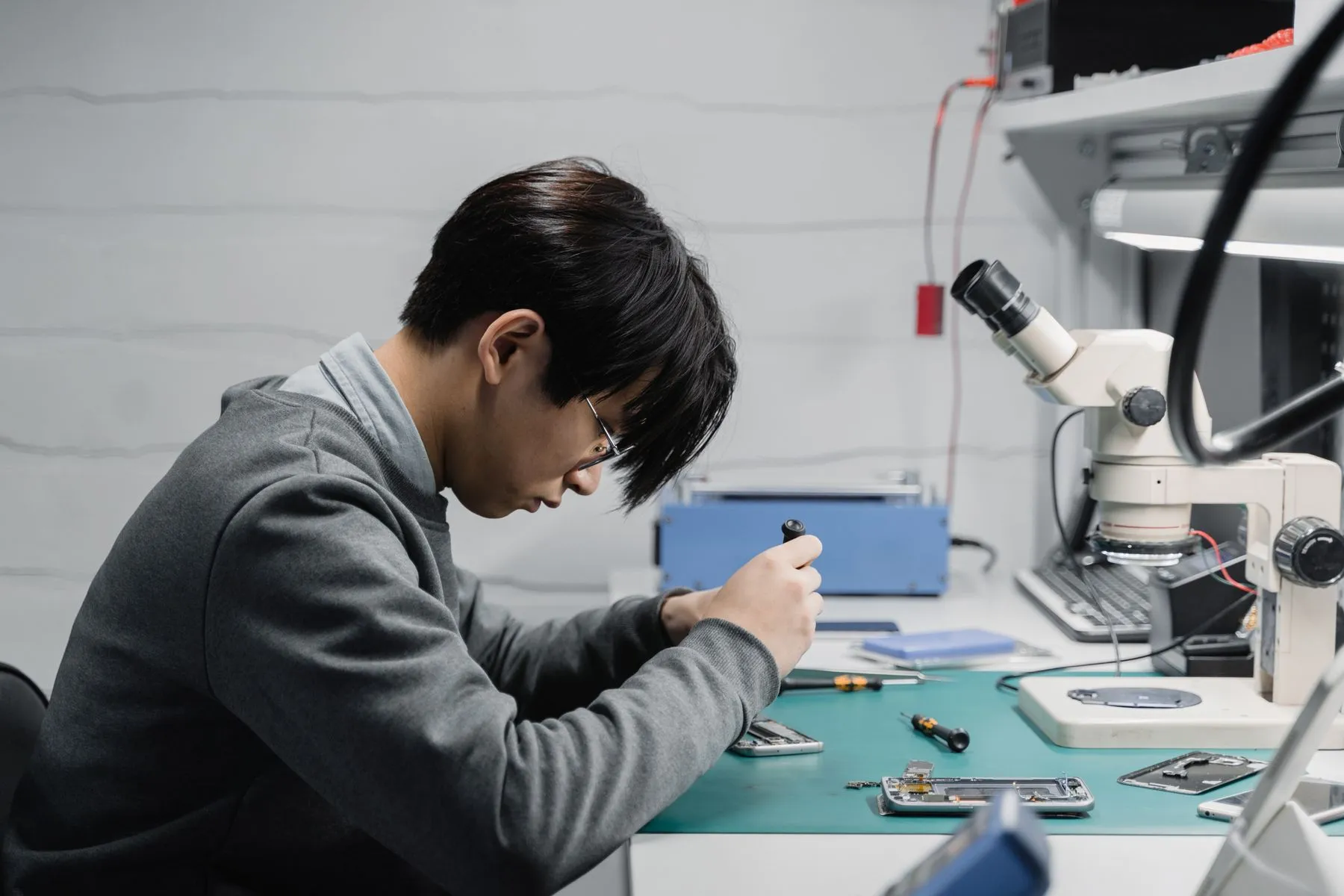Técnico reparando un celular en su mesa de trabajo con microscopio