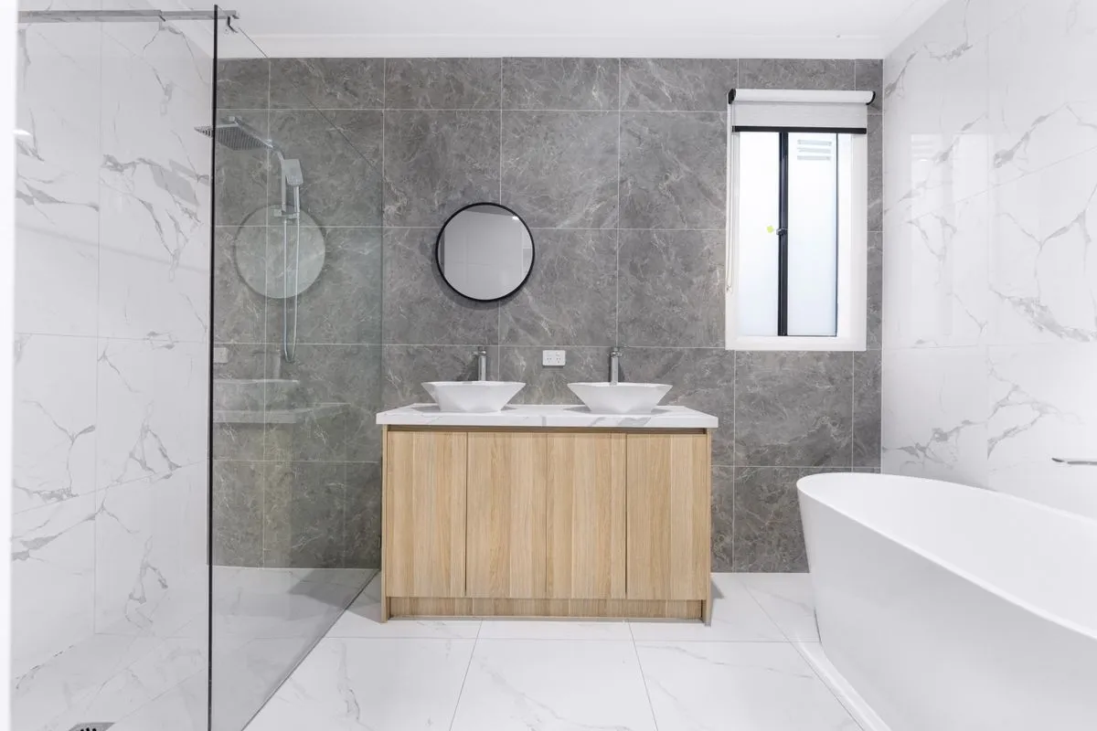 Baño remodelado con porcelanato, mampara de vidrio y doble bacha