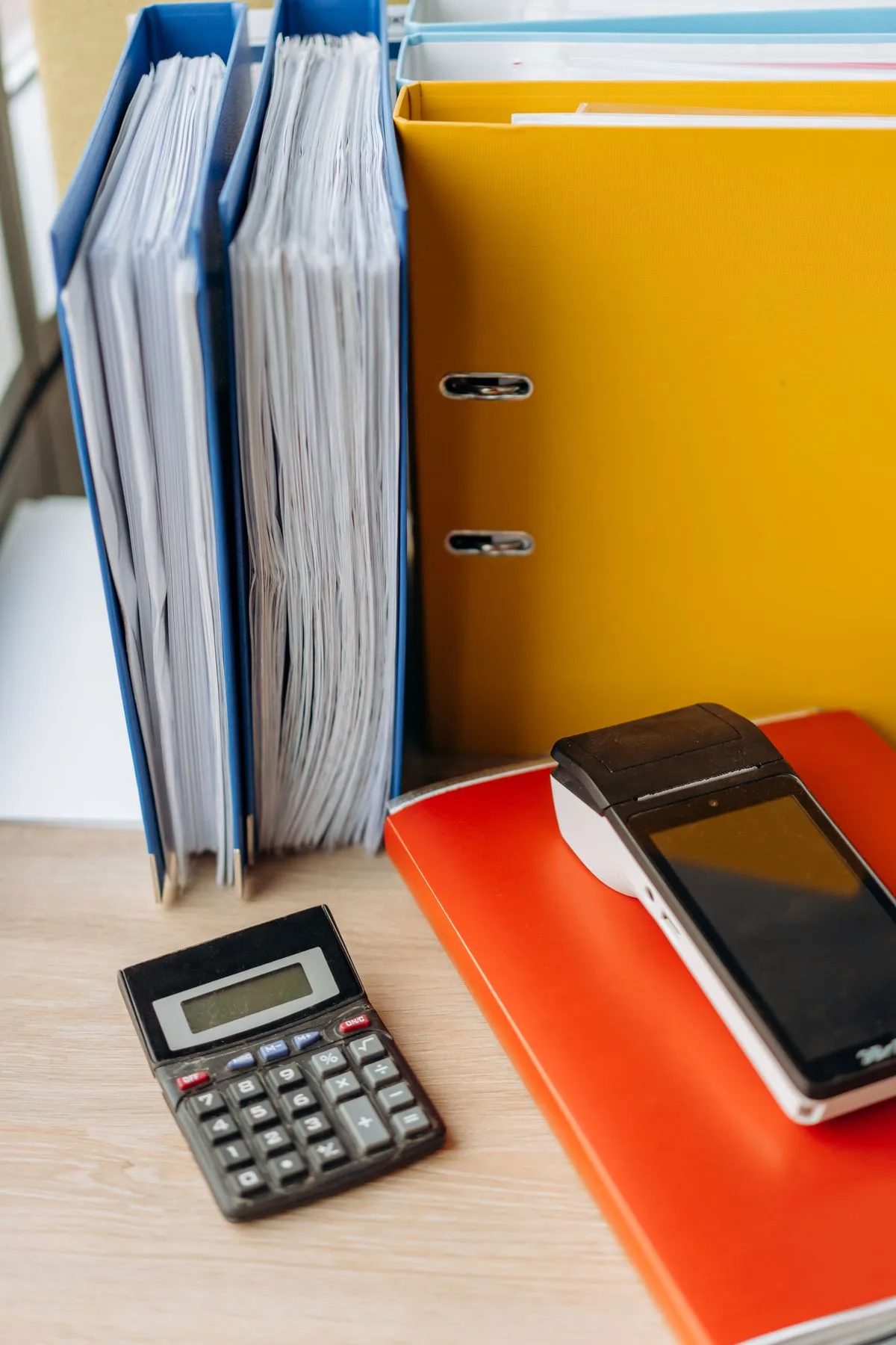 Carpetas archivadoras de colores y una calculadora sobre el escritorio
