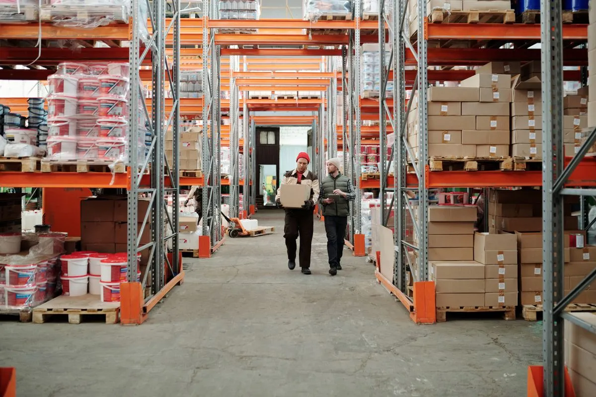 Depósito con estanterías llenas de mercadería y dos operarios