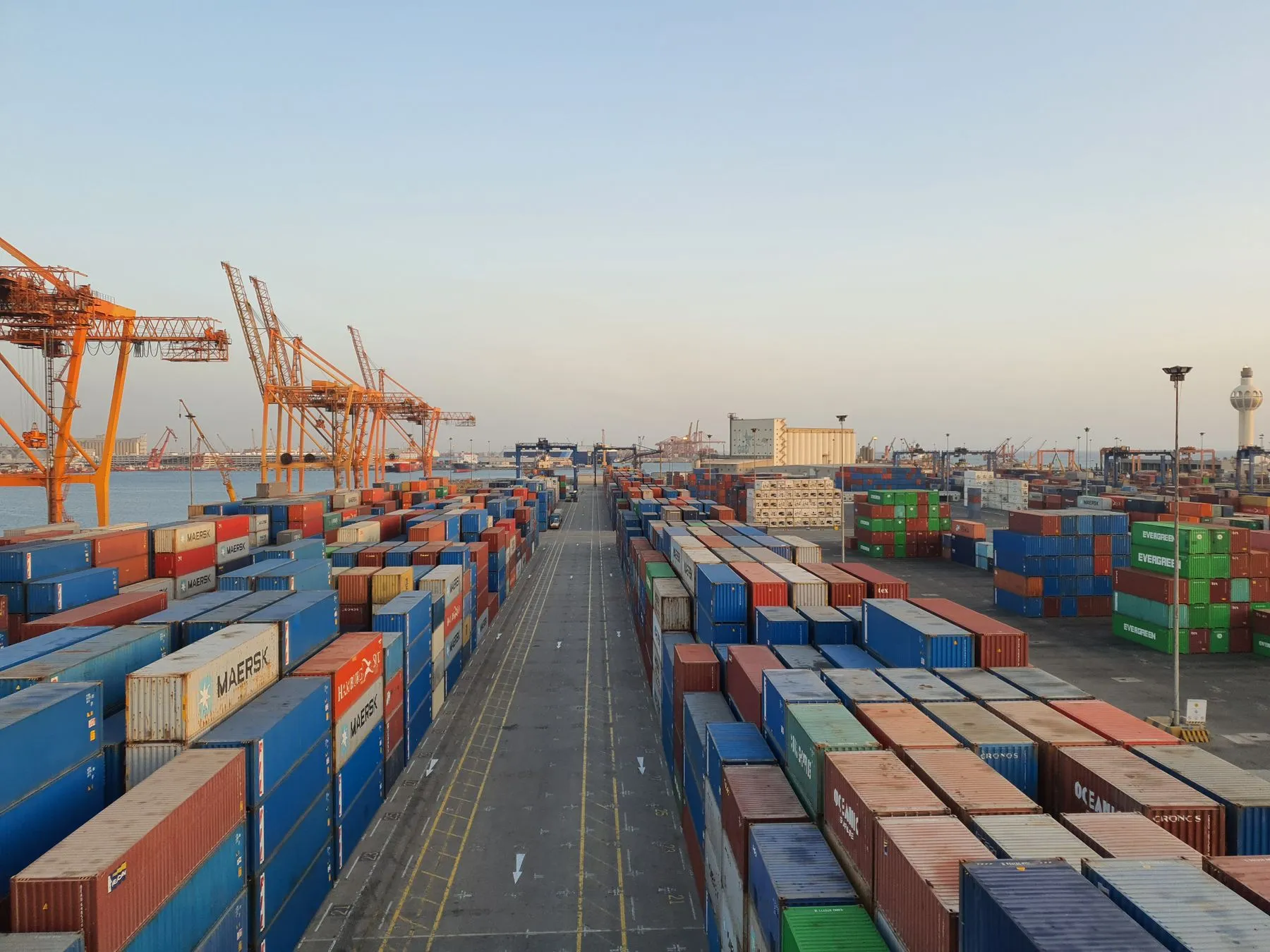 Puerto con contenedores apilados y grúas al amanecer