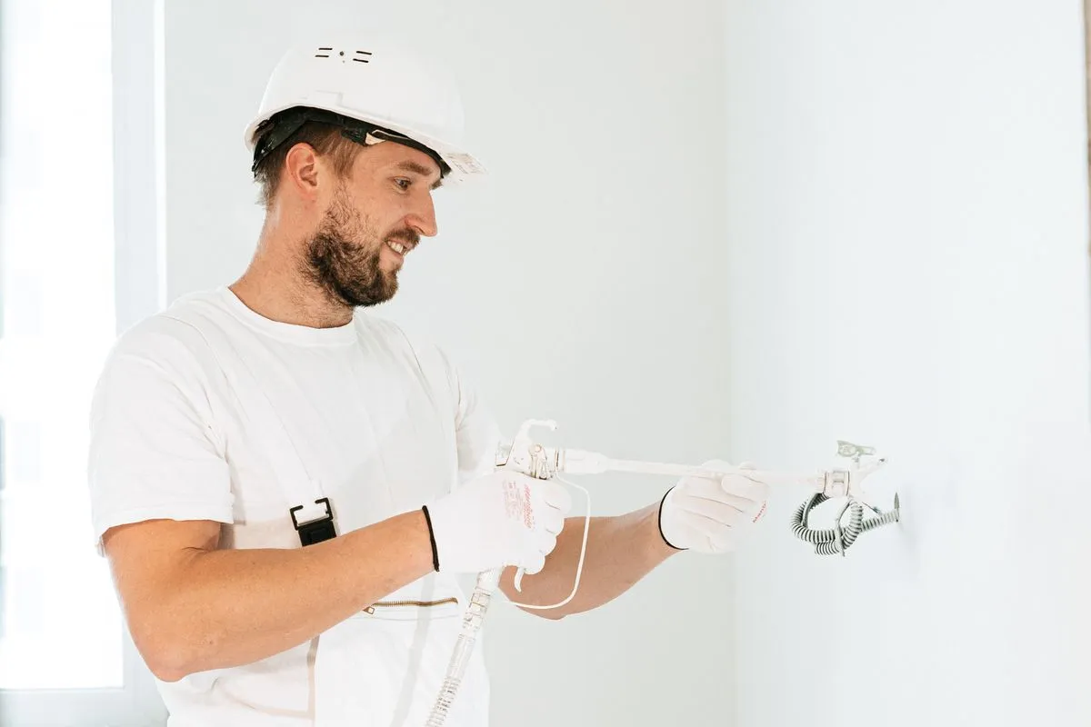 Electricista con casco instalando cableado en una obra nueva