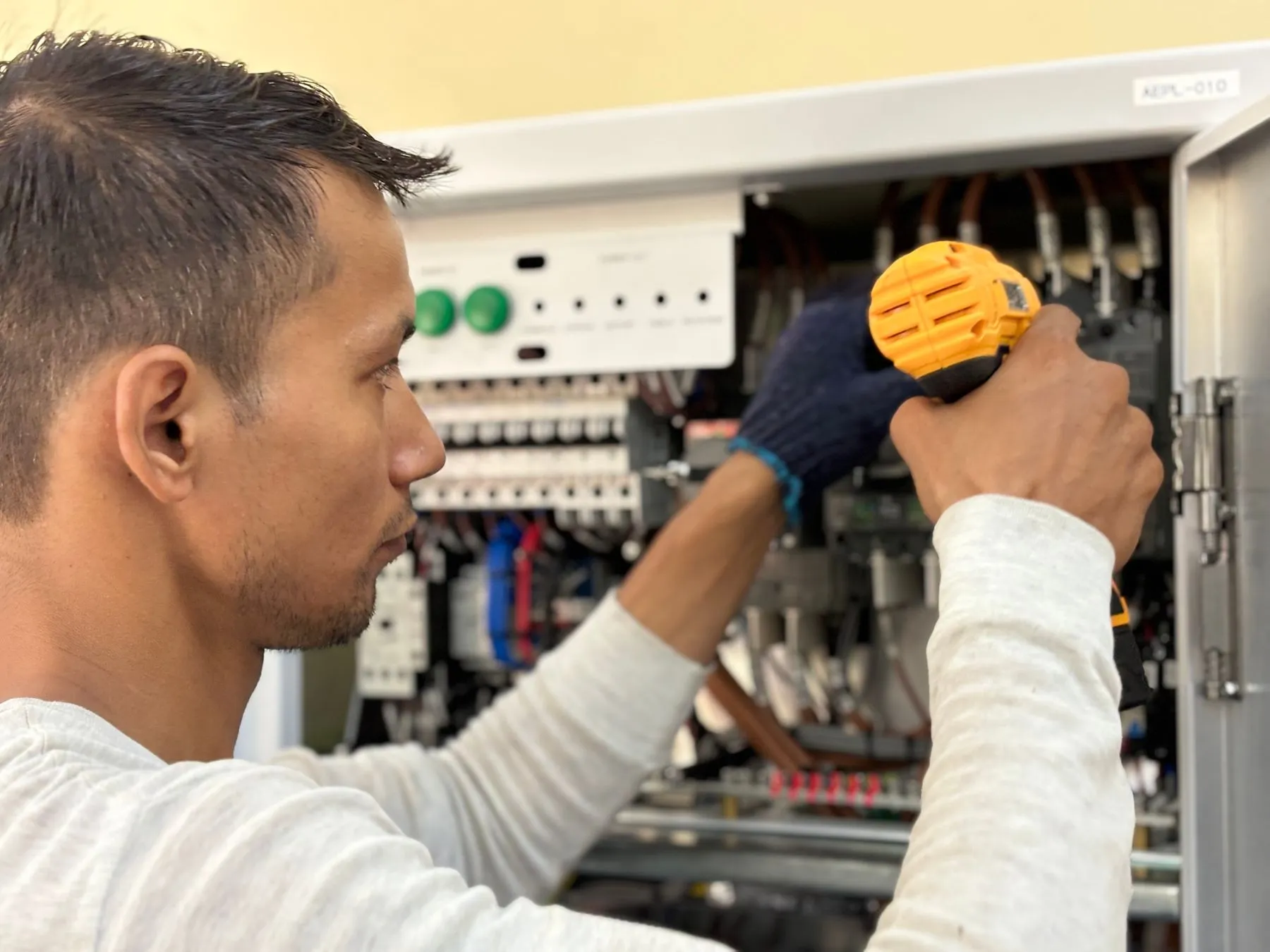 Electricista trabajando con taladro en un tablero eléctrico