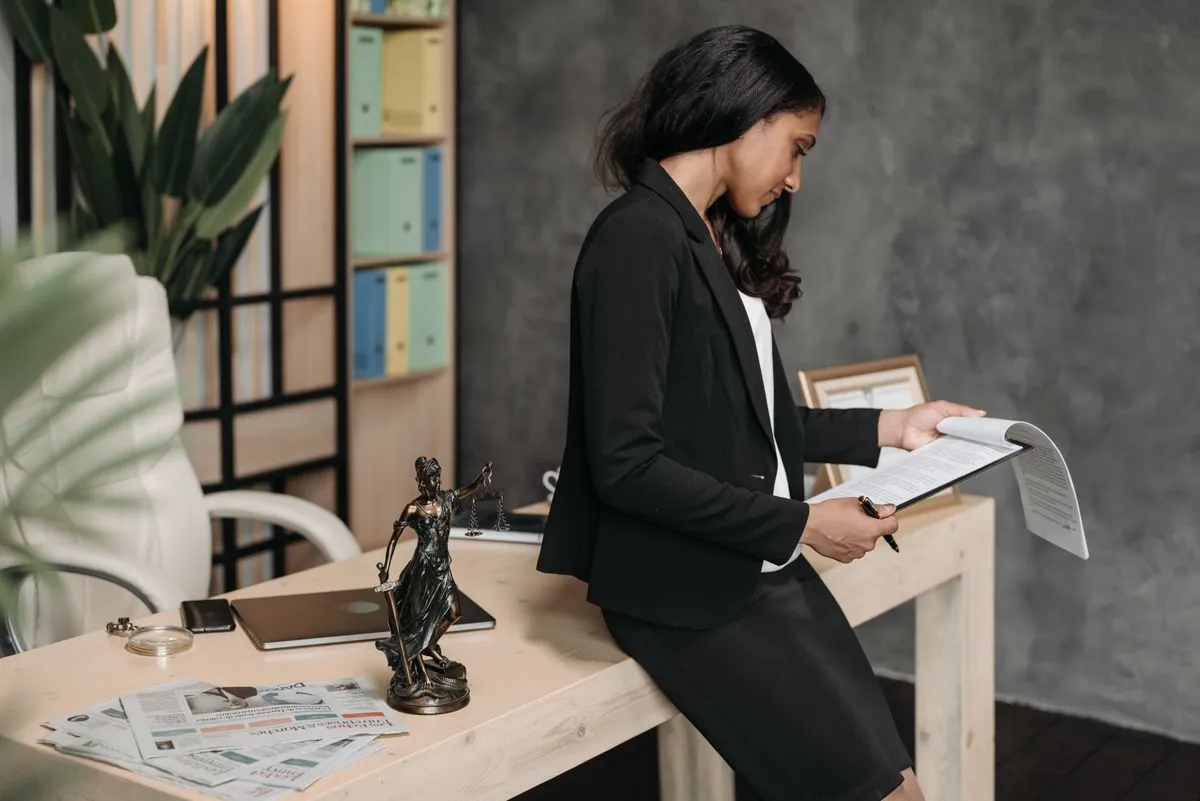 Abogada leyendo un documento apoyada en su escritorio