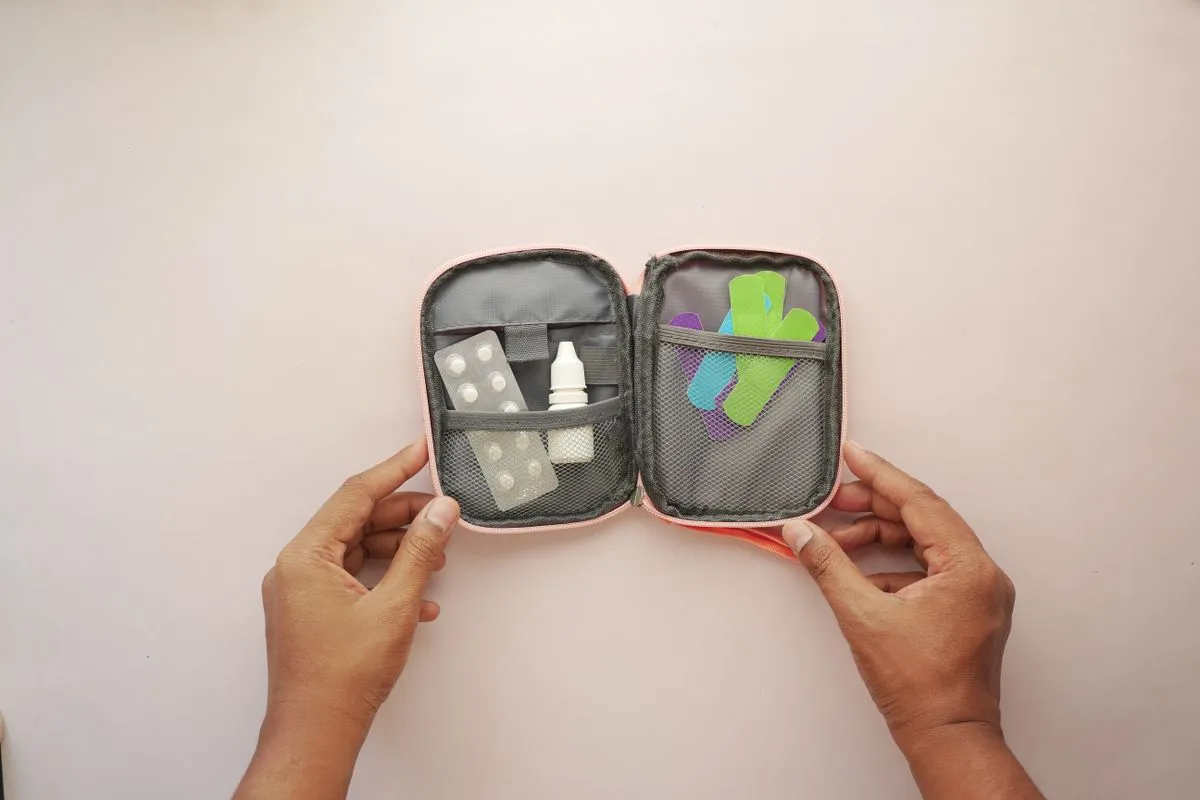 Manos sosteniendo un botiquín abierto con curitas y pastillas