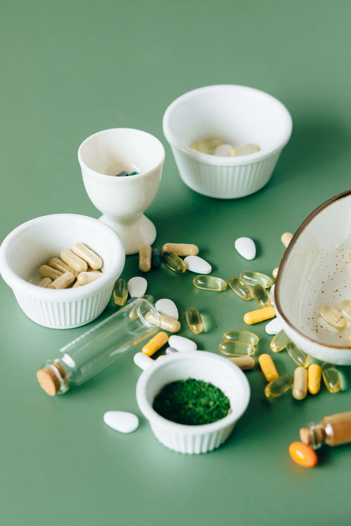 Vitaminas y suplementos en cuencos sobre fondo verde