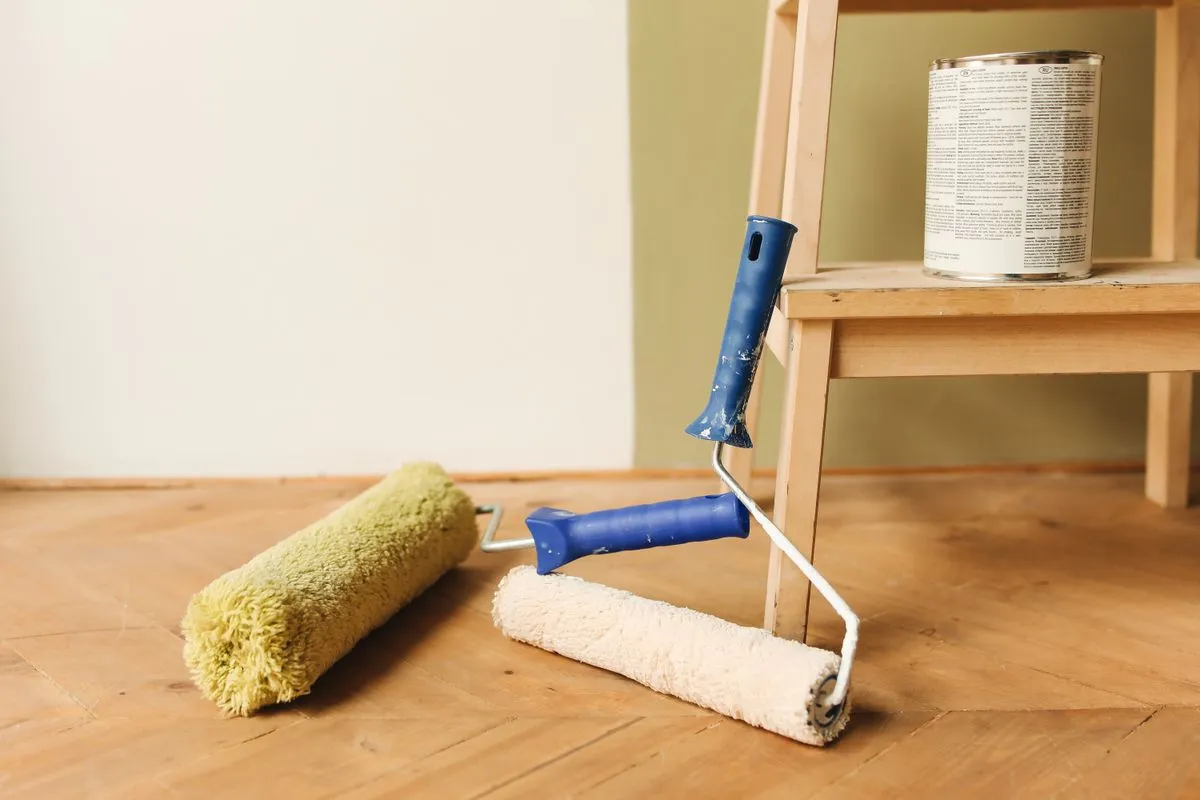 Rodillos de pintura y lata sobre piso de madera