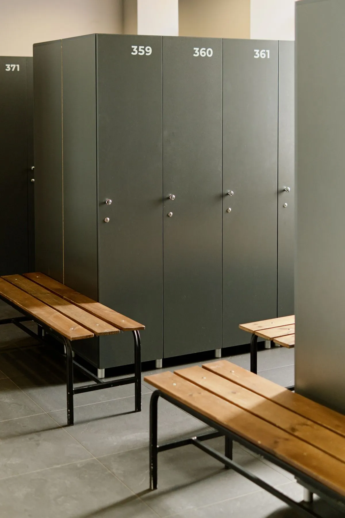 Vestuario con casilleros grises numerados y bancos de madera