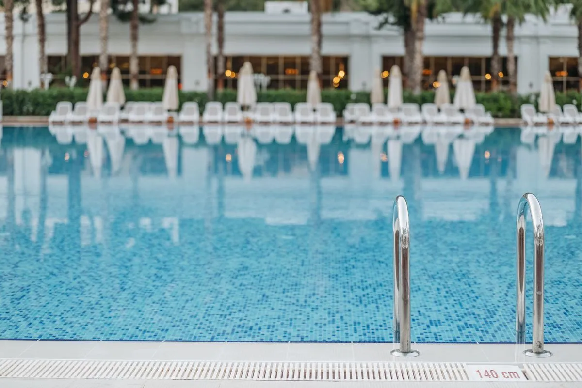 Piscina del hotel con agua turquesa y reposeras al fondo
