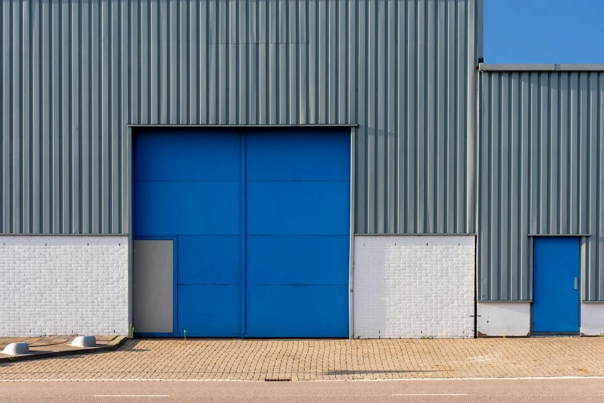 Depósito de chapa con portón grande para camiones y puerta de acceso