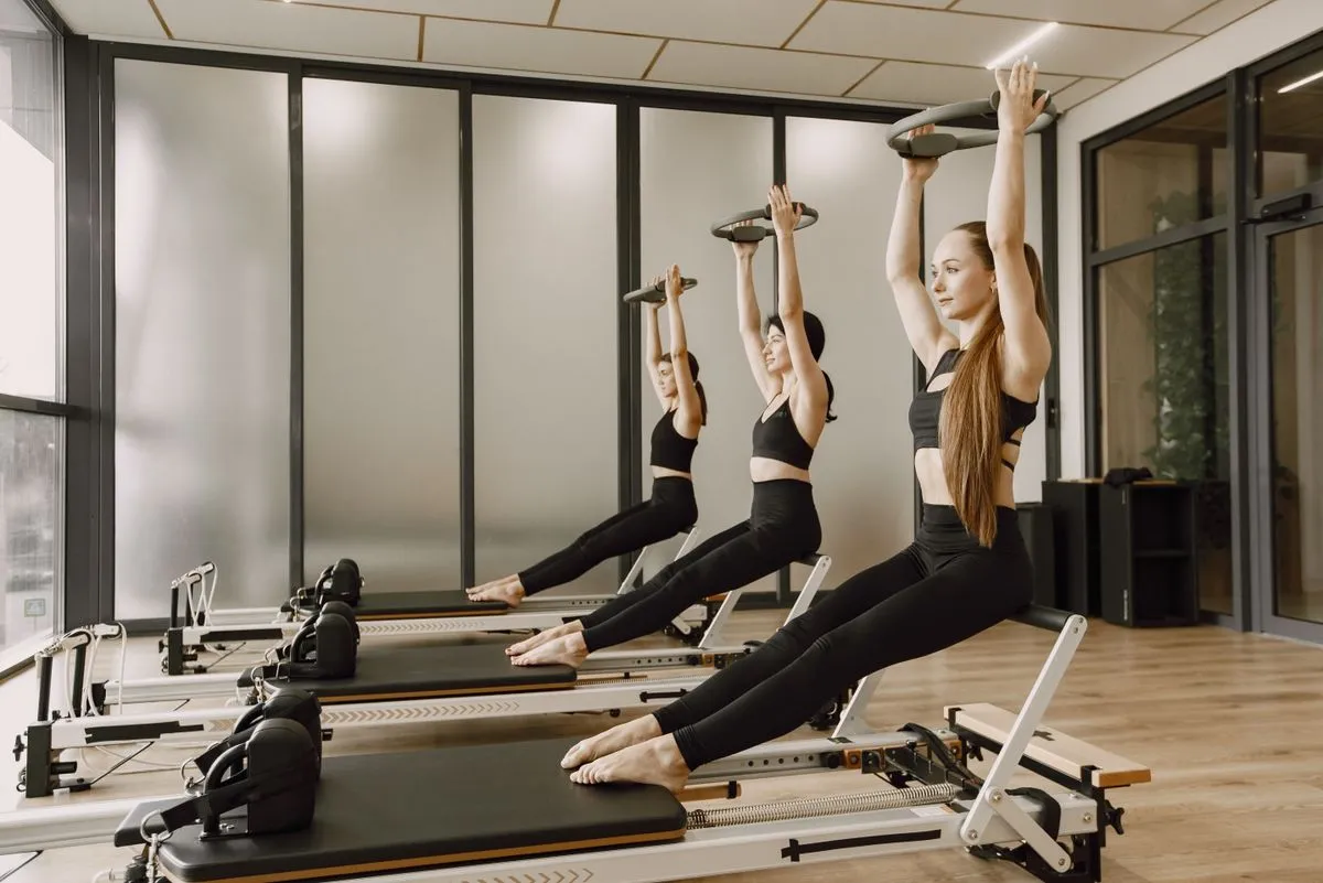 Tres mujeres haciendo pilates en reformers