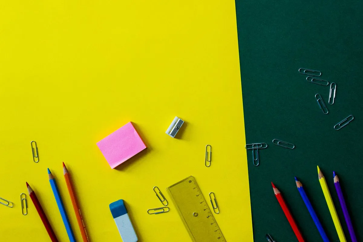 Lápices, regla, clips y notas adhesivas sobre fondo amarillo y verde