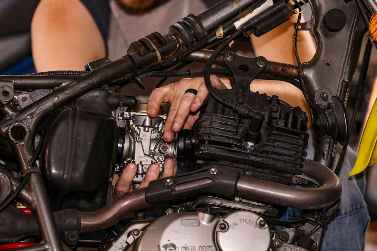 Manos de mecánico reparando el motor de una moto