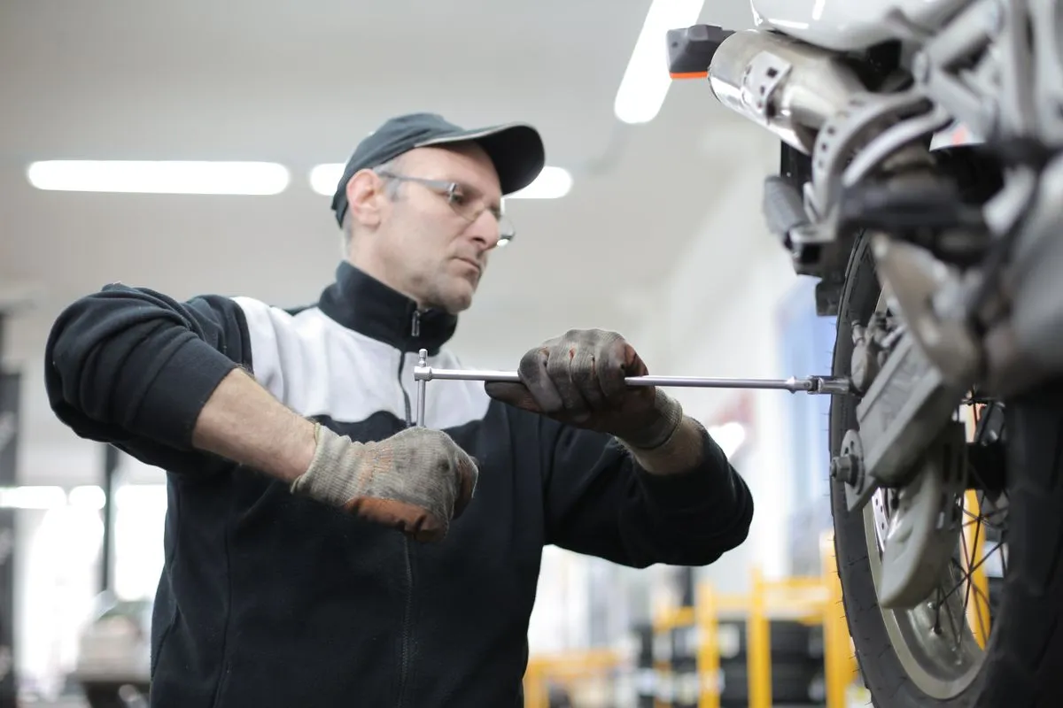 Mecánico ajustando la rueda de una moto en el taller