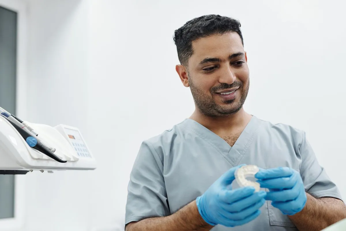 Odontólogo sonriente mostrando un modelo dental