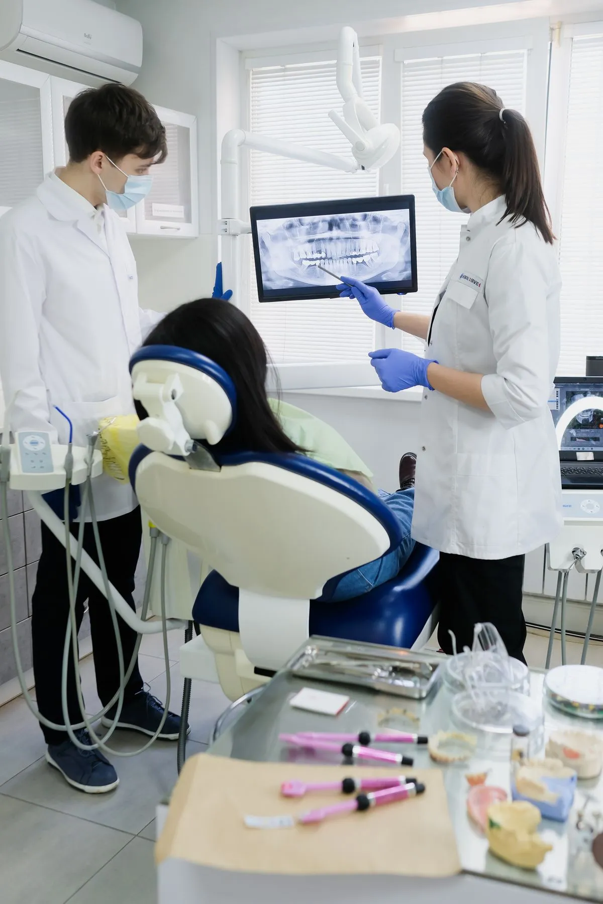 Odontólogos revisando una radiografía dental en la pantalla junto a la paciente