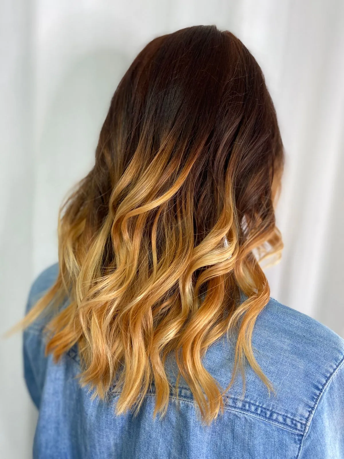 Cabello largo ondulado con degradé de castaño a tonos miel, visto de espaldas