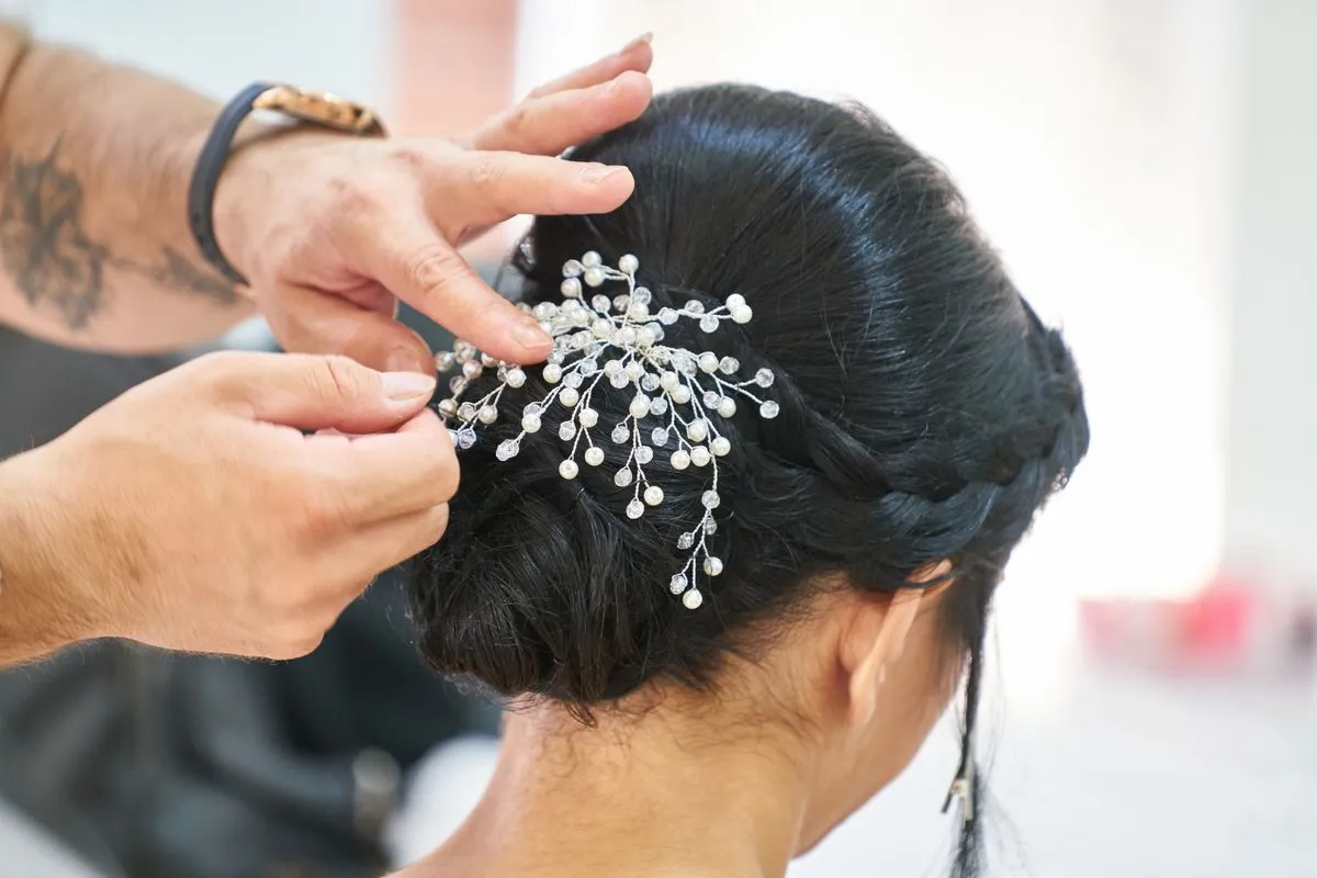 Estilista colocando un tocado brillante en un recogido de novia