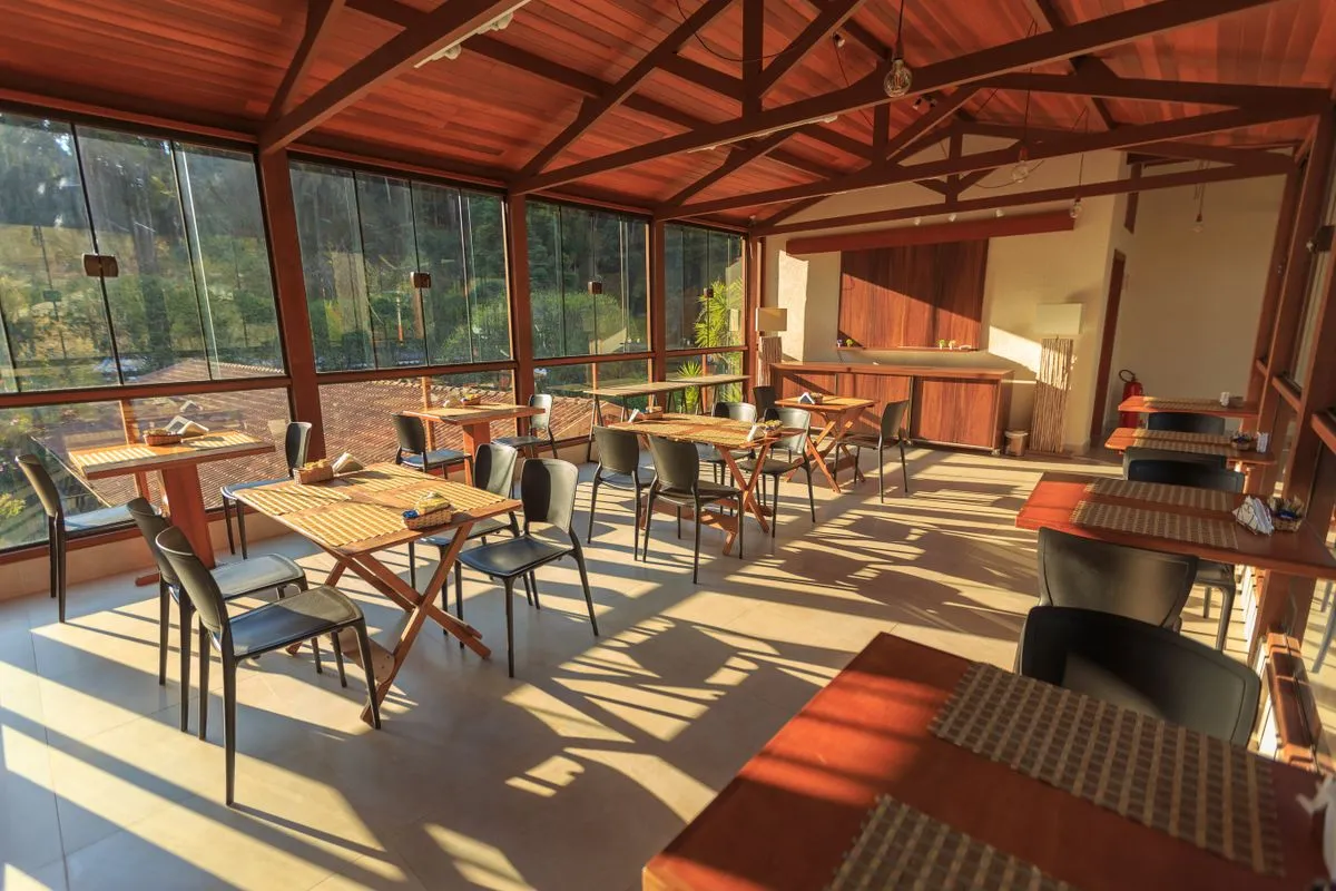Salón con mesas de madera y ventanales iluminado por el sol