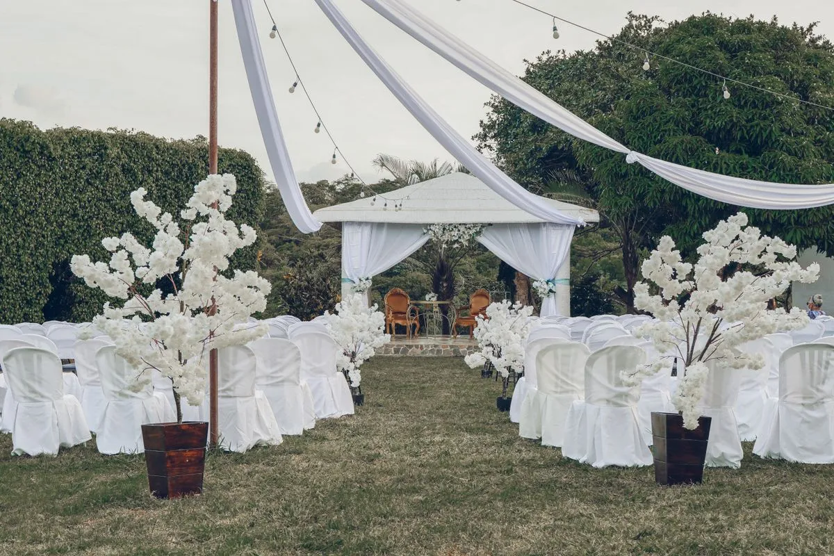 Jardín preparado para una ceremonia con sillas blancas y un gazebo