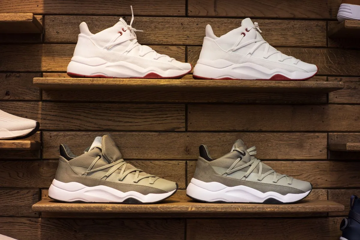 Zapatillas urbanas blancas y beige exhibidas en estantes de madera