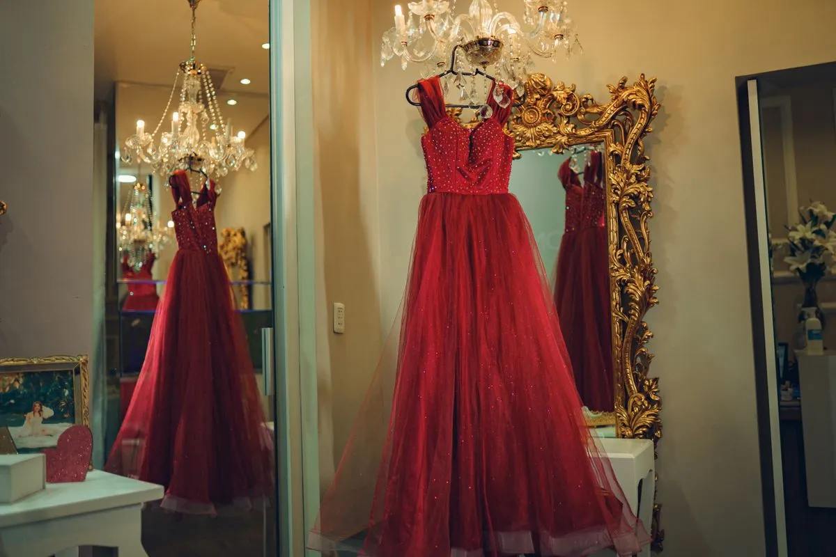 Vestidos de fiesta rojos exhibidos en una boutique con espejo y araña
