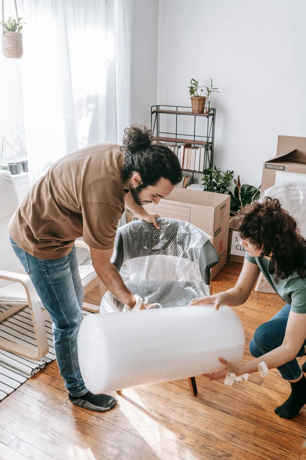 Personas envolviendo un mueble con plástico de burbujas